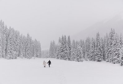 Ein Paar spaziert im Tiefschnee während es schneit