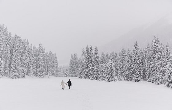 Ein Paar spaziert im Tiefschnee während es schneit
