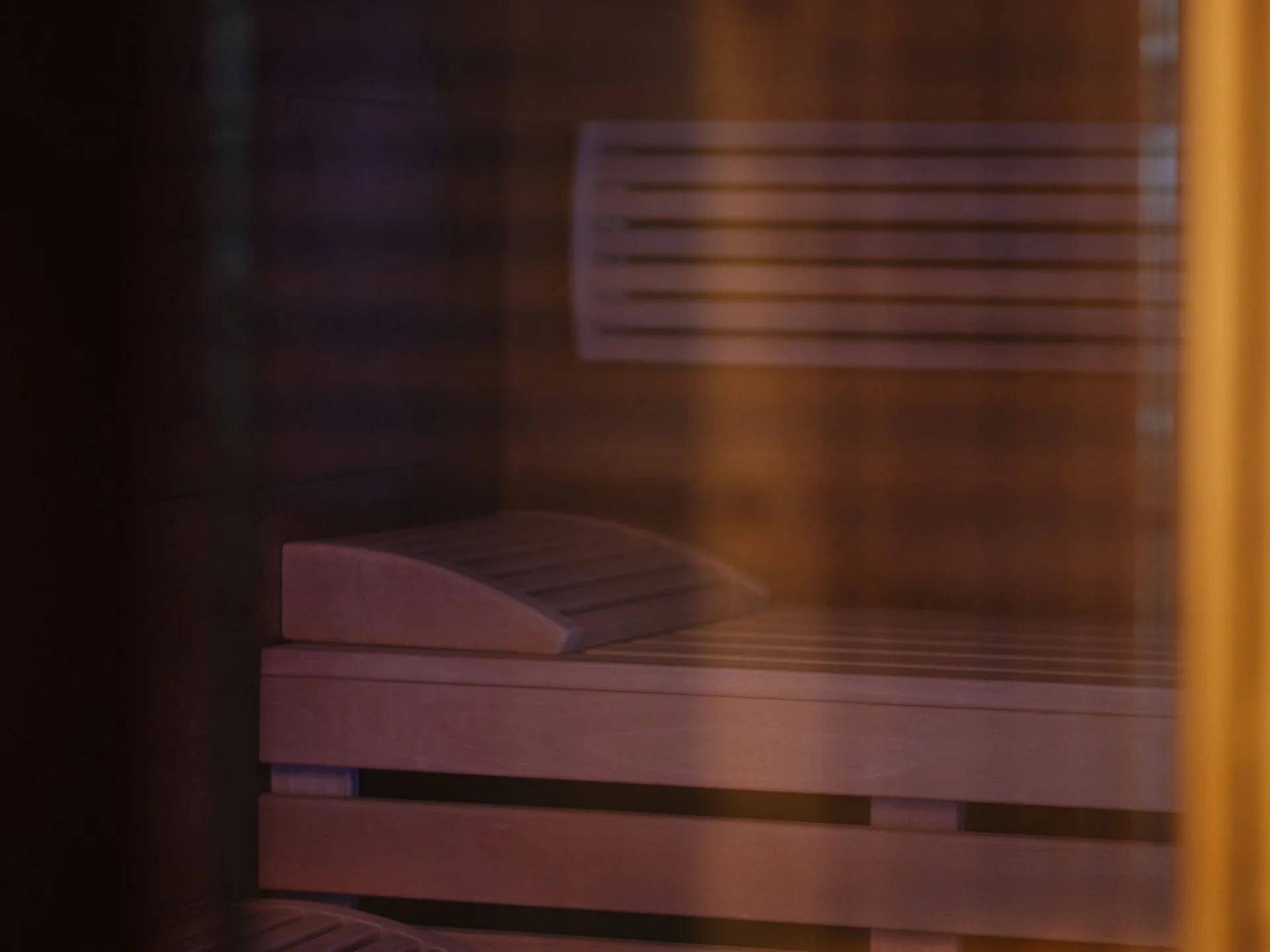 Interior of a sauna with wooden benches and headrest