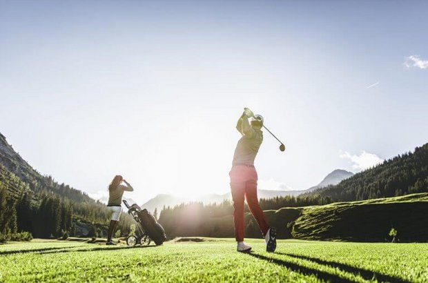 Ein Golfspieler schwingt seinen Schläger nach hintern 