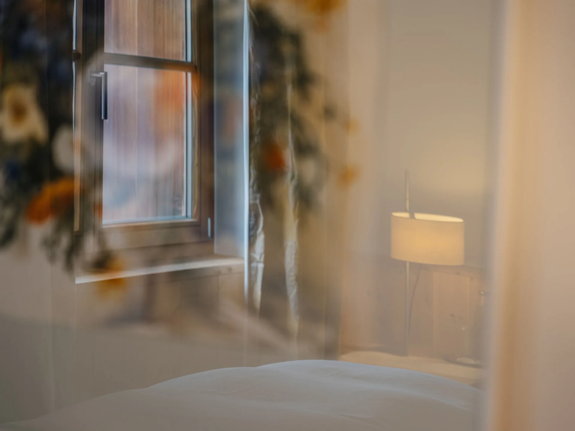 View through window showing bedroom with bedside lamp