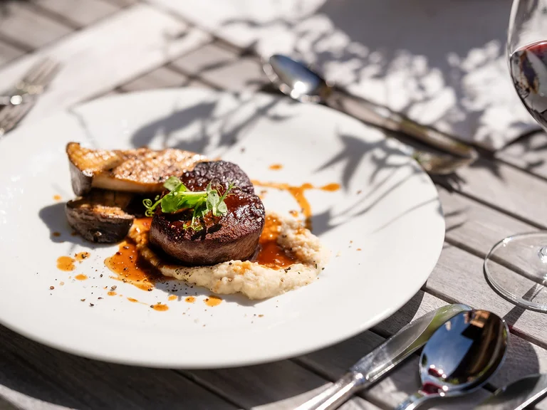 Filetsteak mit Sauce, Gemüse und Rotwein auf Holztisch serviert
