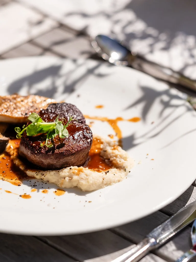 Filetsteak mit Sauce, Gemüse und Rotwein auf Holztisch serviert