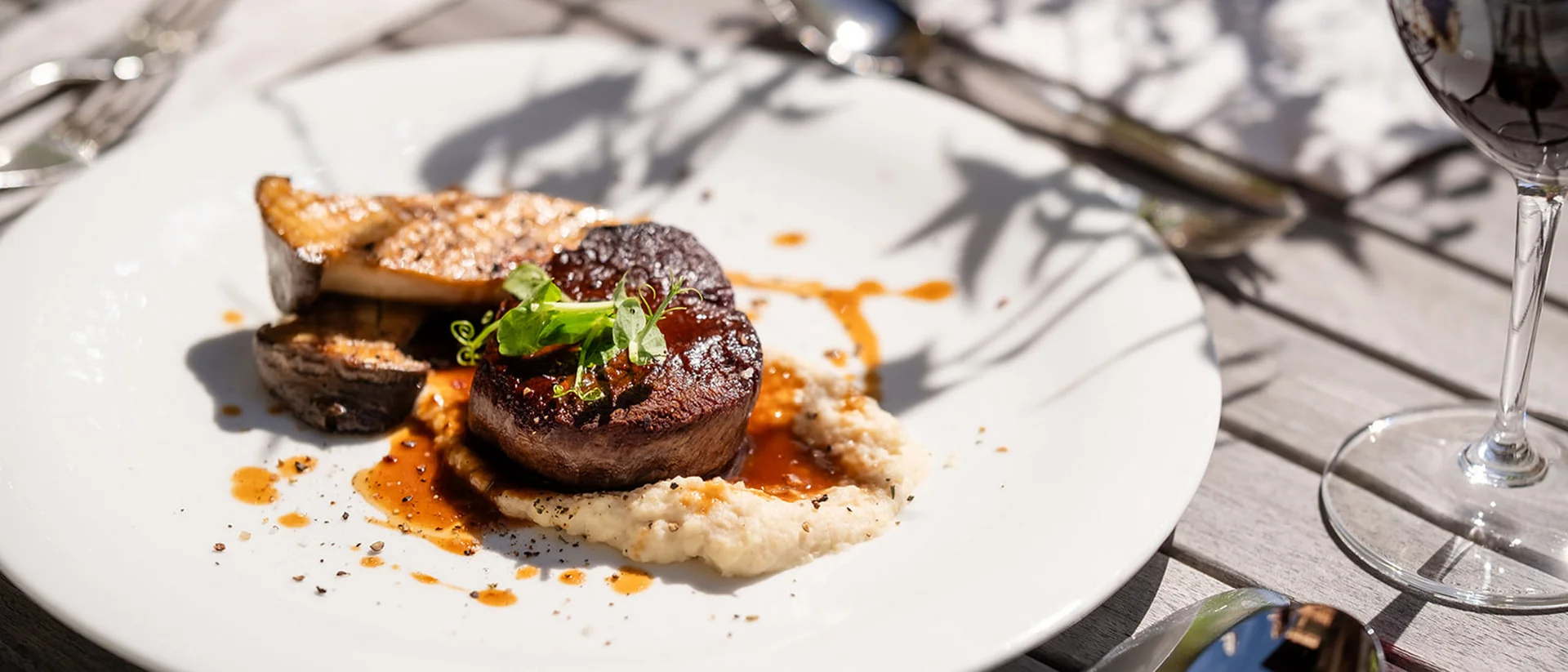 Filetsteak mit Sauce, Gemüse und Rotwein auf Holztisch serviert