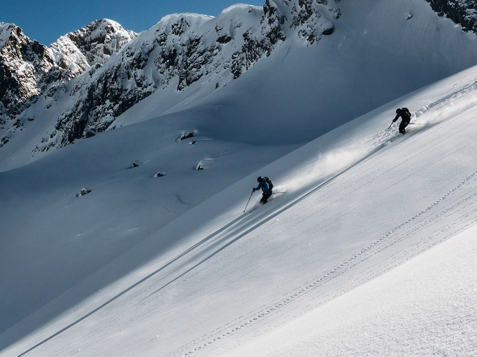 Two skiers skiing down a snowy mountain slope