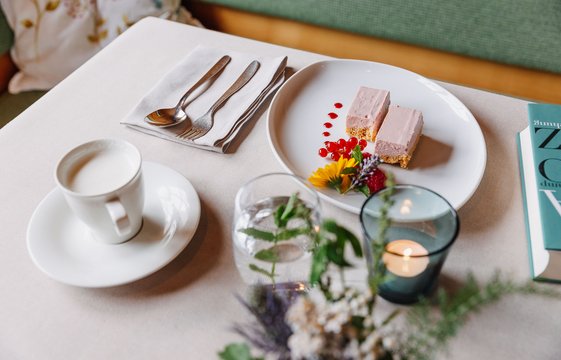 Schön gedeckter tisch mit einer Tasse Kaffee und einer Erdbeersahneschnitte. 