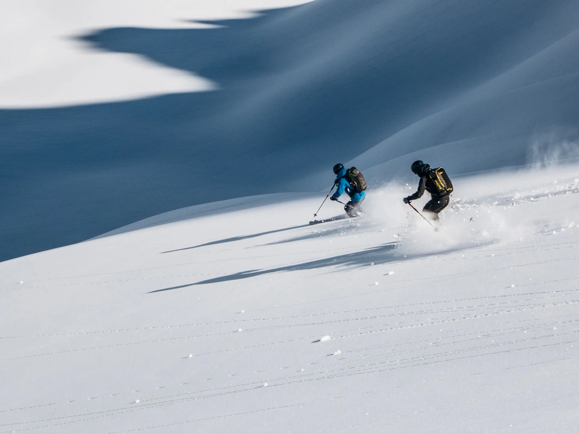 Two skiers skiing through fresh powder snow on a snowy slope