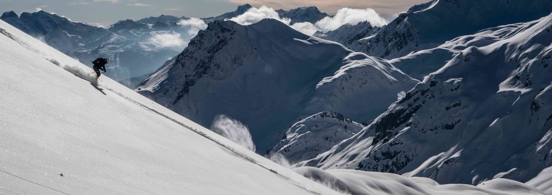 Ein Skifahrer fährt im Tiefschnee den Berg hinunter 