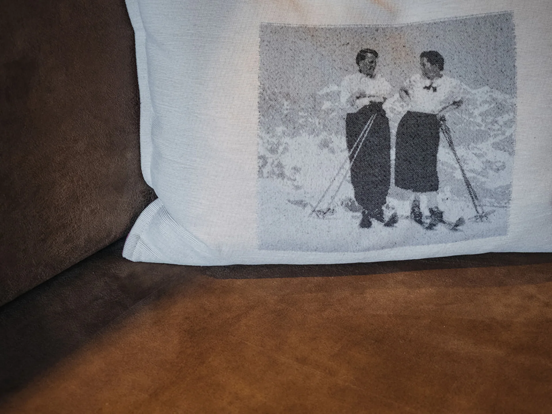 Cushion with image of two women in vintage clothes on brown sofa