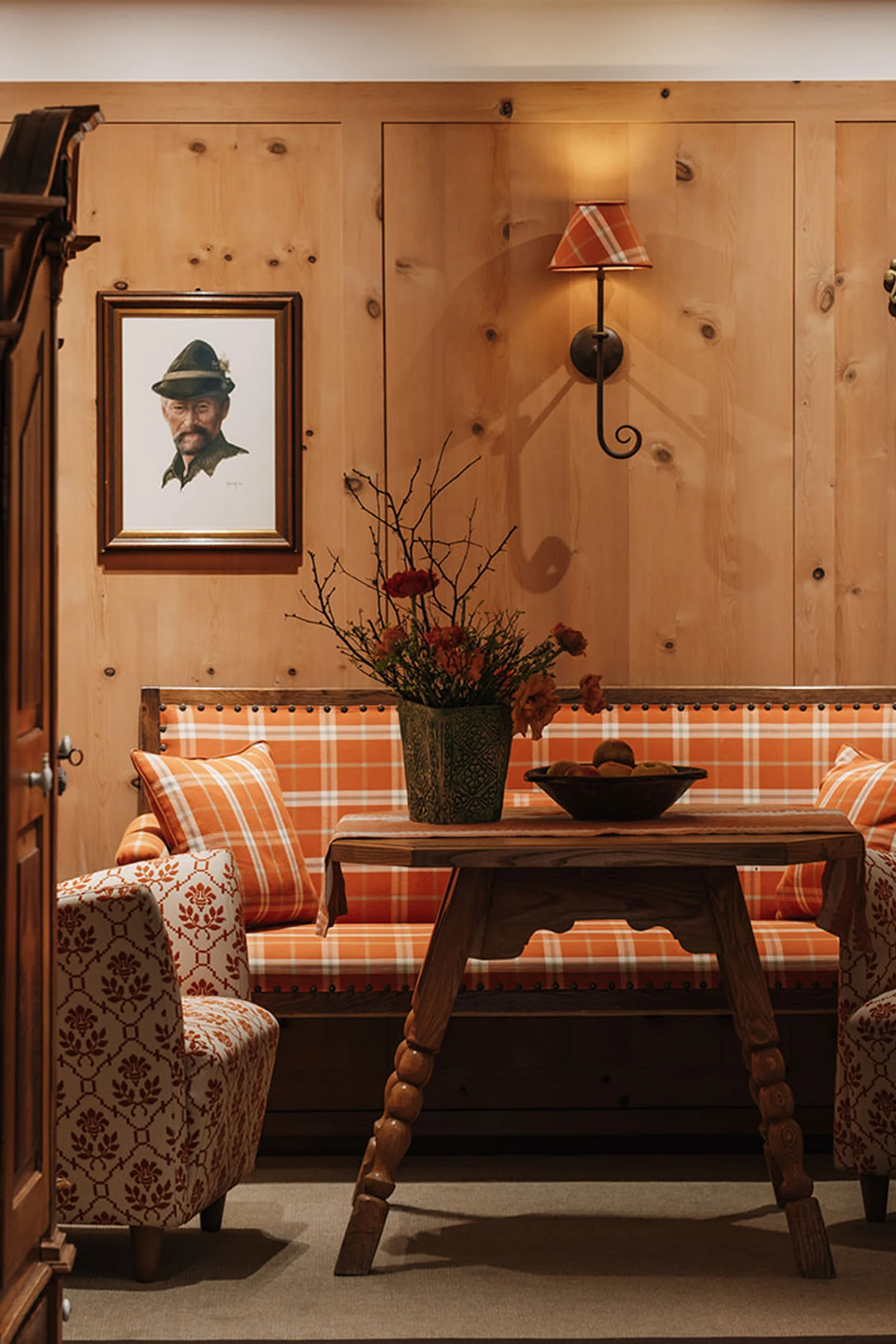 Gemütliche Sitzecke mit Holzvertäfelung, karierten Polstern und Jagdtrophäen an der Wand