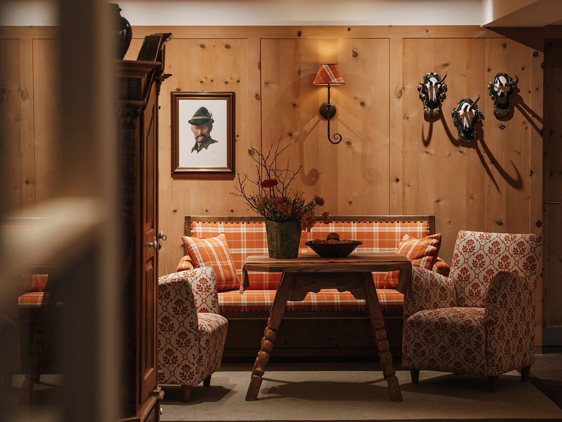 Cozy seating nook with wood paneling, plaid cushions, and hunting trophies on wall