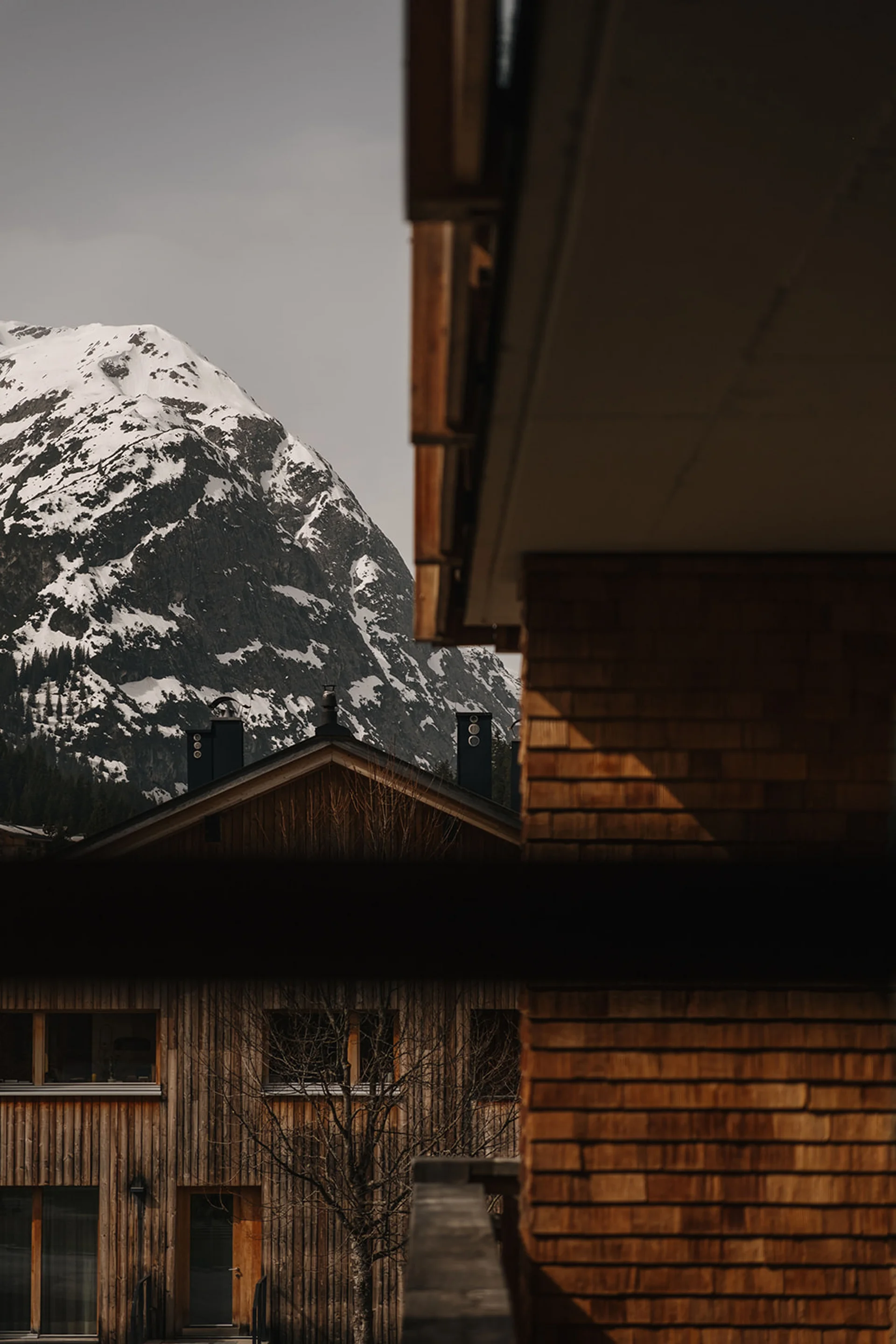 Holzhäuser vor schneebedecktem Berg im ruhigen Dorf