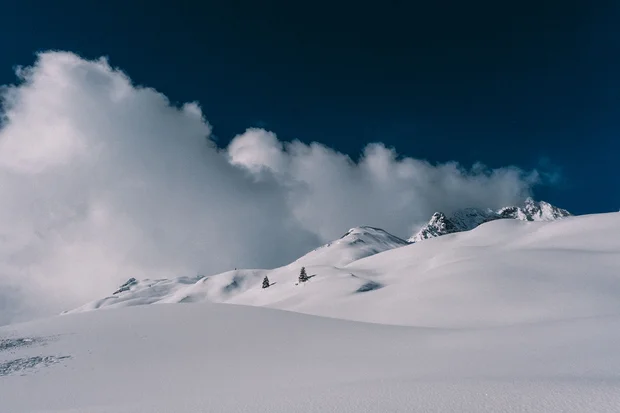 Schneebedeckte Berge unter einem bewölkten dunkelblauen Himmel