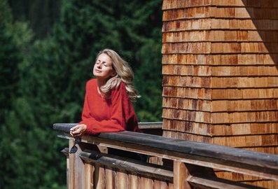 Eine Frau steht am Balkon und genießt die Sonne 