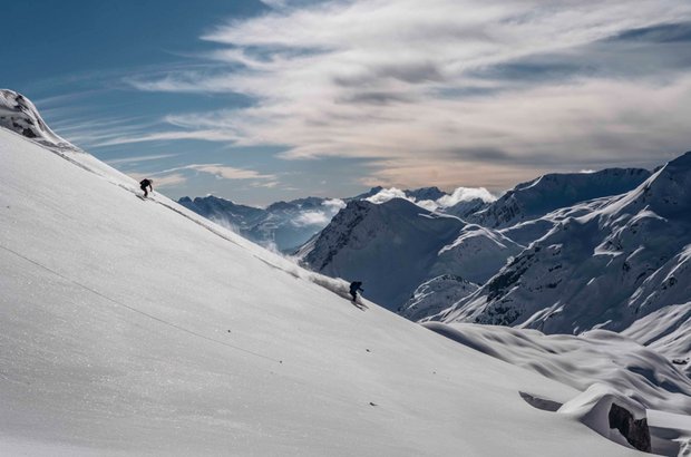 Eine Person fährt mit Skiern einen verschneiten Berg hinunter