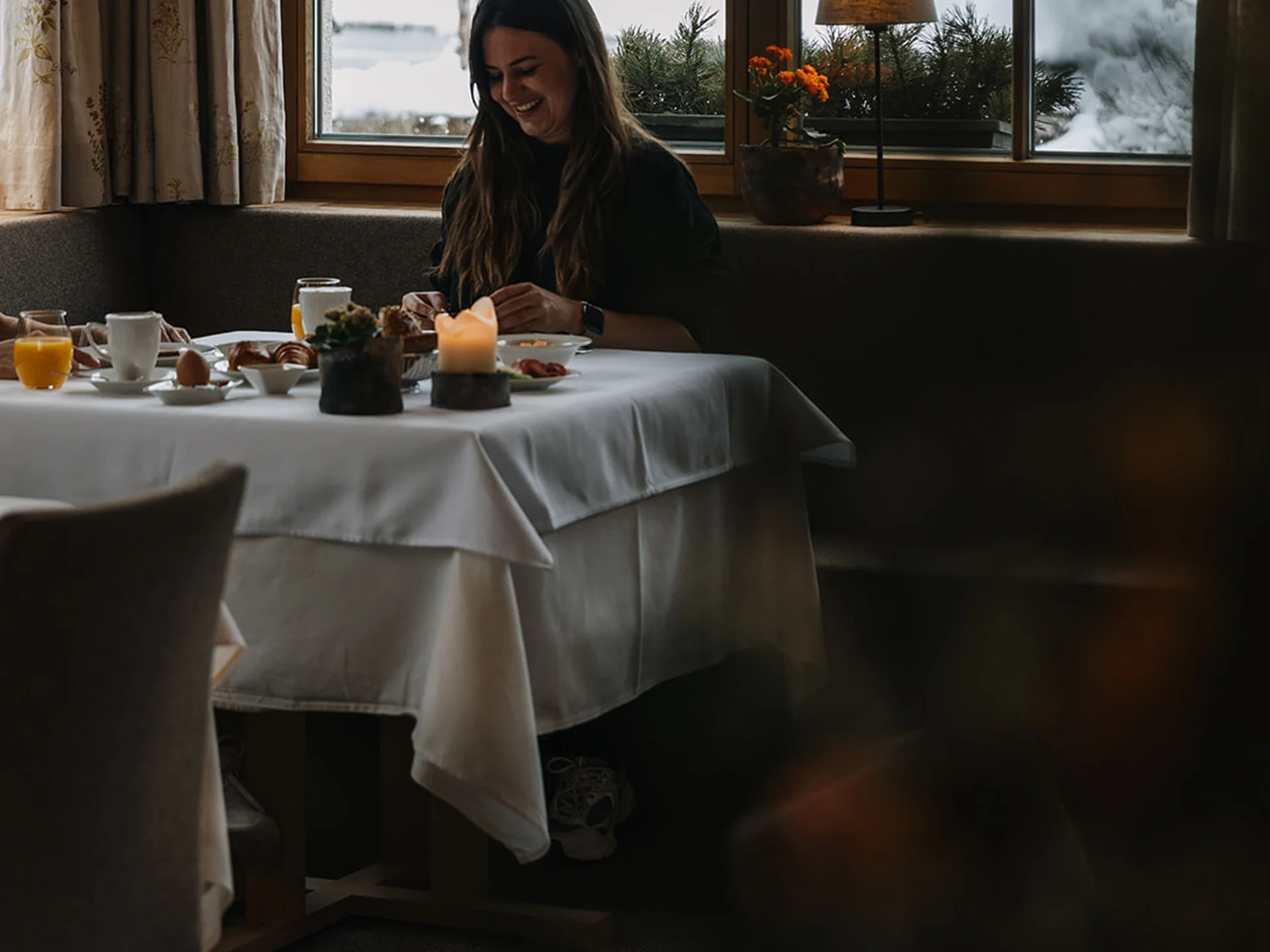 Woman enjoying breakfast inside with snowy landscape visible through window