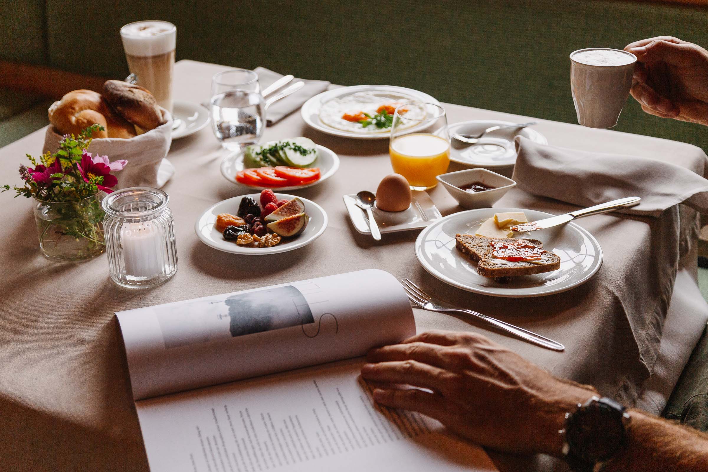 Frühstückstisch gedeckt mit frischem Obst, Brot, gekochtes Ei, Kaffee und frisch gepresstem Orangensaft.